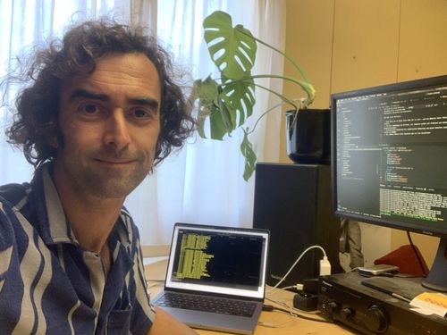 Thomas sitting in front of his desk, smiling